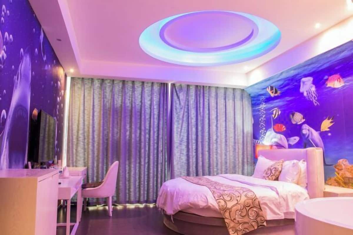 A bedroom with a bed, a desk, and curtains.