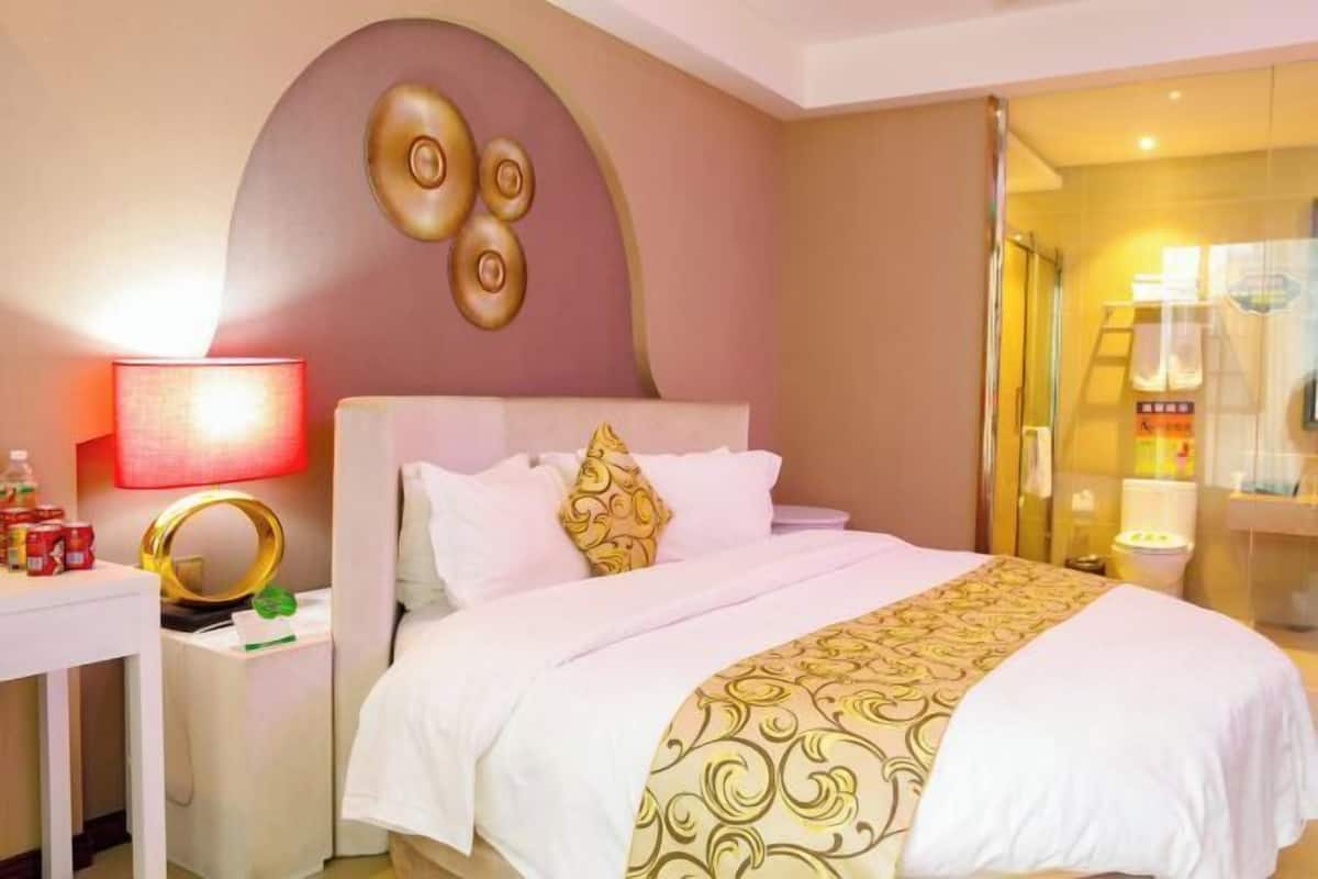 A hotel room with a bed, bedside tables, a lamp, and a mirror.