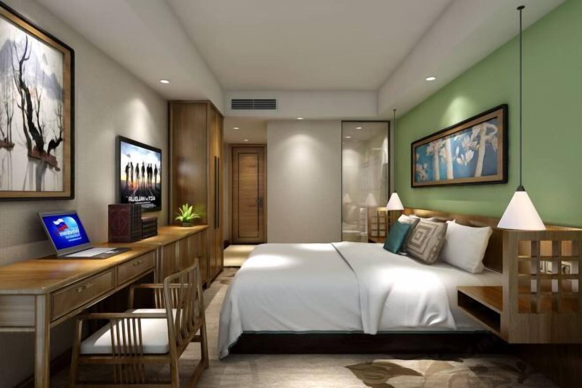 A modern hotel room with a bed, desk, chair, and artwork on the walls.