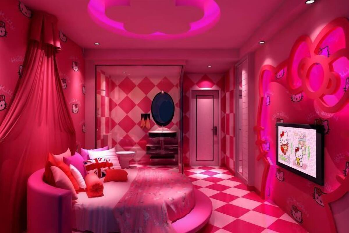 A pink-themed room with a bed, a mirror, and a TV screen.