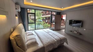 A bedroom with a large bed, a TV mounted on the wall, and a window offering a view of the outdoors. - Shangli Ancient Town juxianzhuang farmhouse (Ya'an)