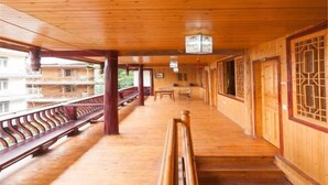 A wooden corridor with benches, a table, and chairs, leading to a balcony with a railing. - Shangli Ancient Town juxianzhuang farmhouse (Ya'an)