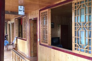 A wooden corridor with open doors leading to rooms, a chair, and a television in one room. - Shangli Ancient Town juxianzhuang farmhouse (Ya'an)