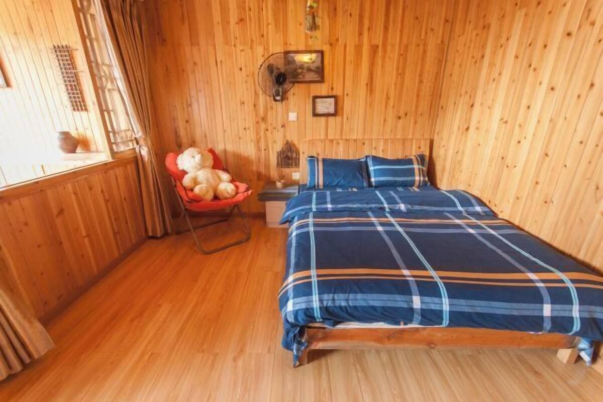 A wooden-paneled room with a bed, a chair, and a window.