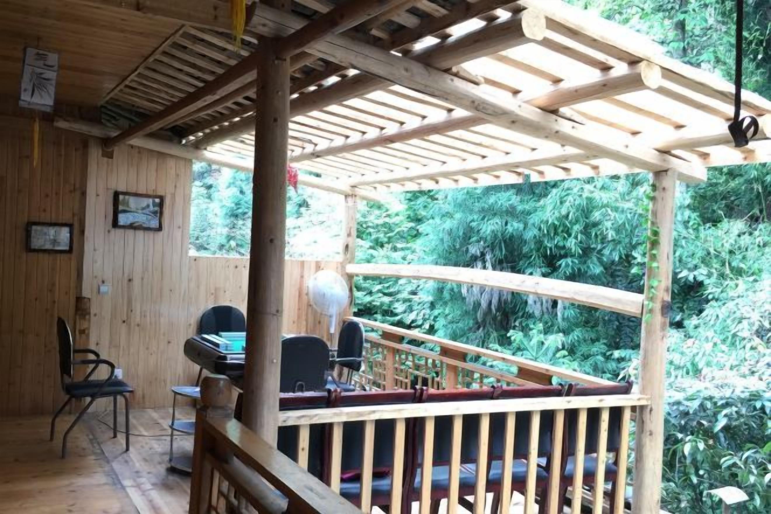 Una terraza de madera con barandilla, una mesa y sillas.