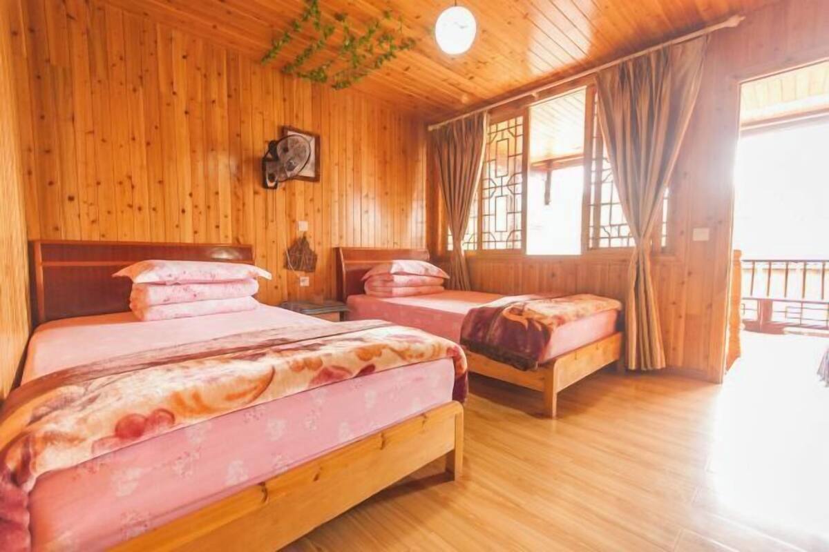 A wooden cabin with two beds, a clock, and a window with curtains.