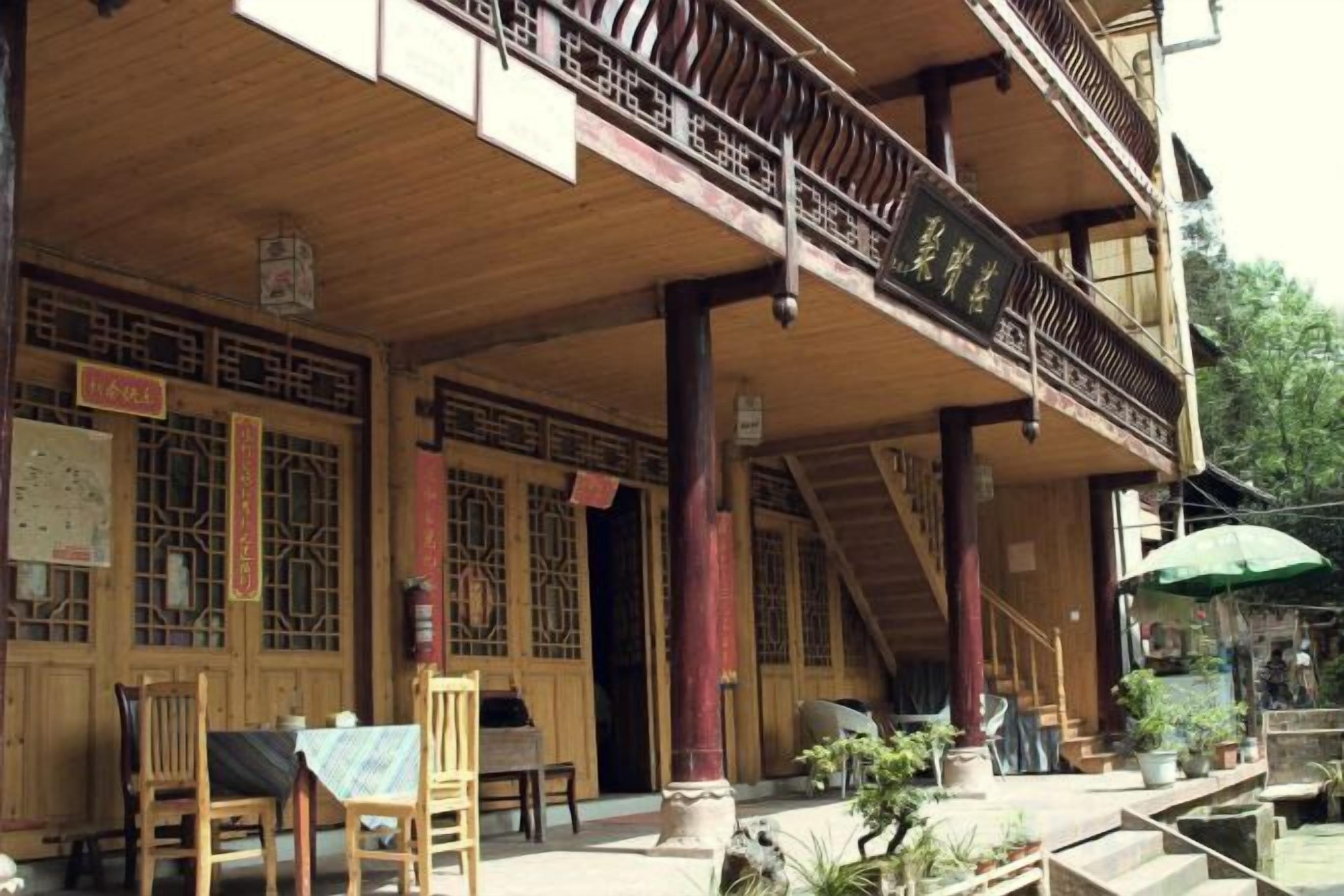 A traditional wooden building with a covered porch, multiple doors, and a staircase leading to an upper level.