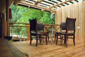 A wooden deck with a table and chairs, surrounded by a wooden fence, overlooking a lush green landscape. - Shangli Ancient Town juxianzhuang farmhouse (Ya'an)