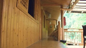 A wooden corridor with a covered end and a view of greenery outside. - Shangli Ancient Town juxianzhuang farmhouse (Ya'an)