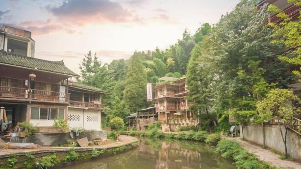 A traditional building with a balcony, a pond in the foreground, and dense greenery in the background. - Shangli Ancient Town juxianzhuang farmhouse (Ya'an)