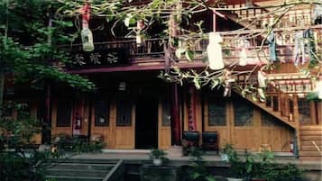 Un edificio tradicional con una escalera de madera, un balcón y plantas en macetas.