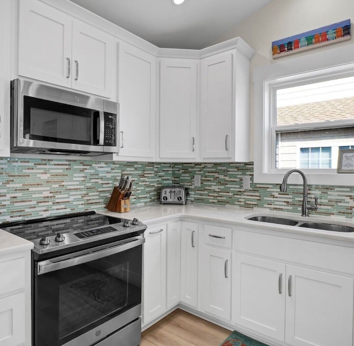 A modern kitchen with white cabinets, stainless steel appliances, and a tiled backsplash.