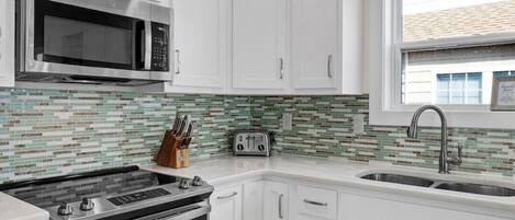 A modern kitchen with white cabinets, stainless steel appliances, and a tiled backsplash.