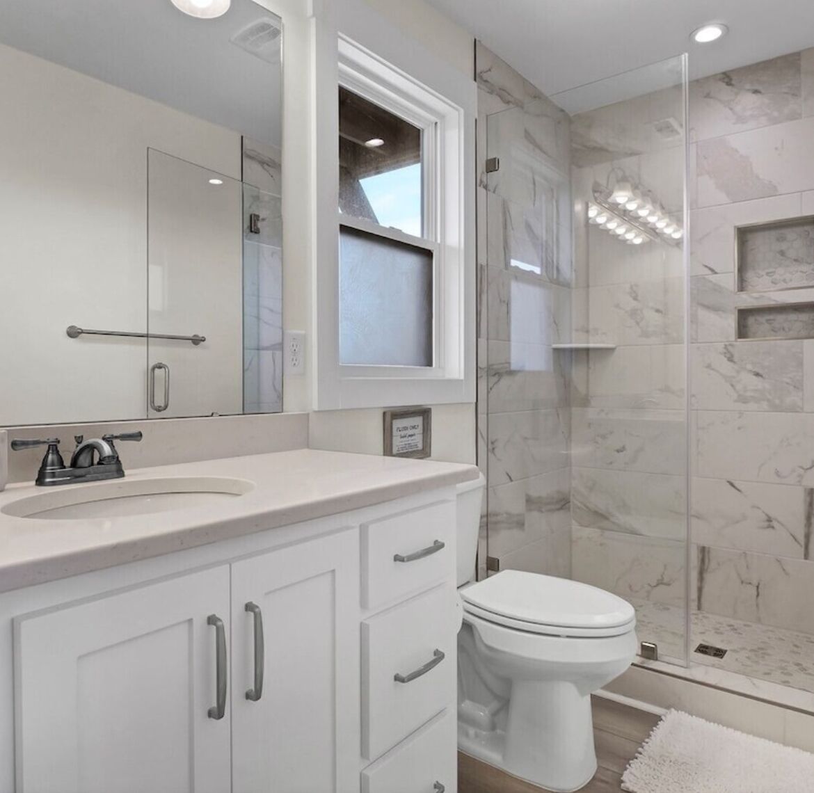 Un baño moderno con un lavamanos blanco, un inodoro y una cabina de ducha de vidrio.