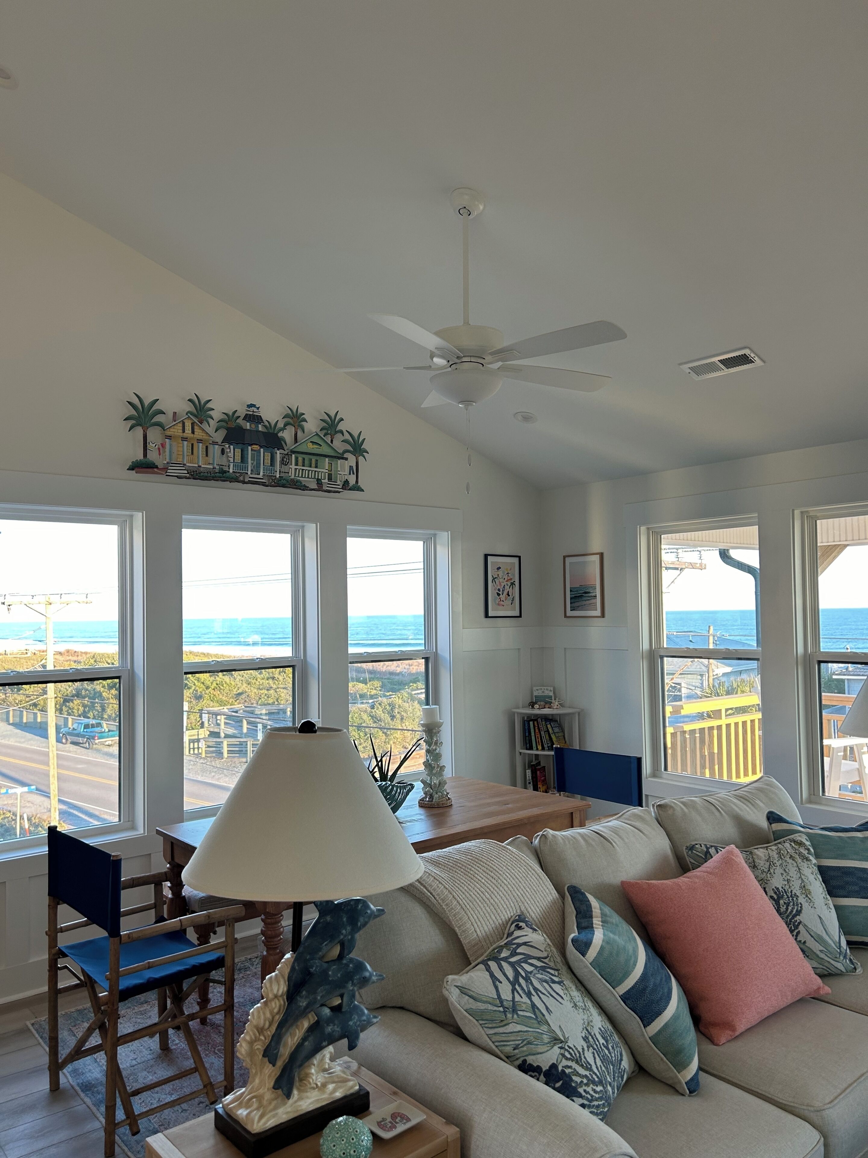 A spacious living room with a large window offering a view of the ocean and a model train display above the windows.