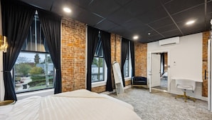 Ein Hotelzimmer mit einem großen Bett, einem Spiegel, einem Schreibtisch und Blick nach draußen.