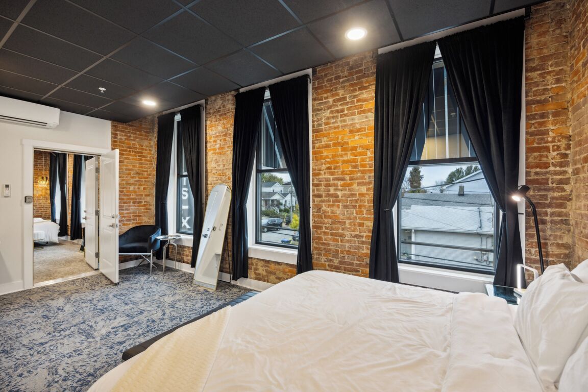 Una habitación de hotel con una cama grande, un muro de ladrillo y una ventana con cortinas.