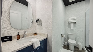 Un baño moderno con tocador, lavamanos, espejo e inodoro.