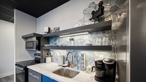 Una cocina moderna con un lavamanos de acero inoxidable, una cafetera y un microondas.