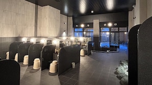 A modern bathroom with multiple sinks, a large mirror, and a stone wall. - Hotel Route Inn Grand Chichibu (Chichibu)