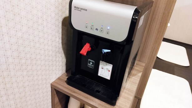 A water dispenser with a control panel, a red button, and a label in a foreign language. - Hotel Route Inn Grand Chichibu (Chichibu)