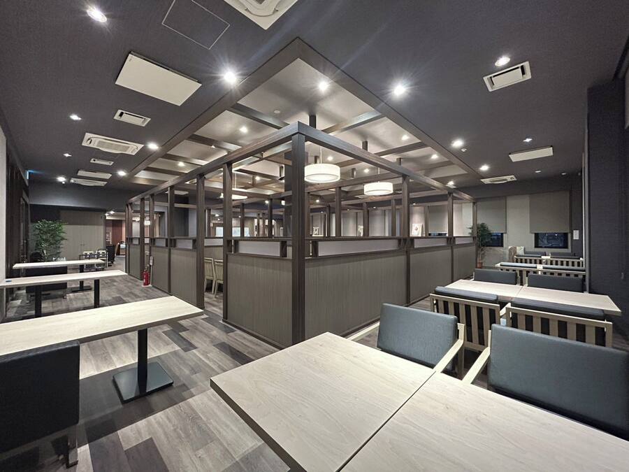 Un espacio de oficina moderno con cubículos, mesas de reuniones e iluminación empotrada.