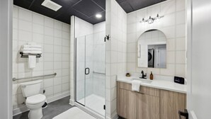 A modern bathroom with a glass-enclosed shower, a toilet, and a vanity with a mirror.