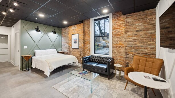A modern bedroom with a bed, a leather sofa, and a round table.