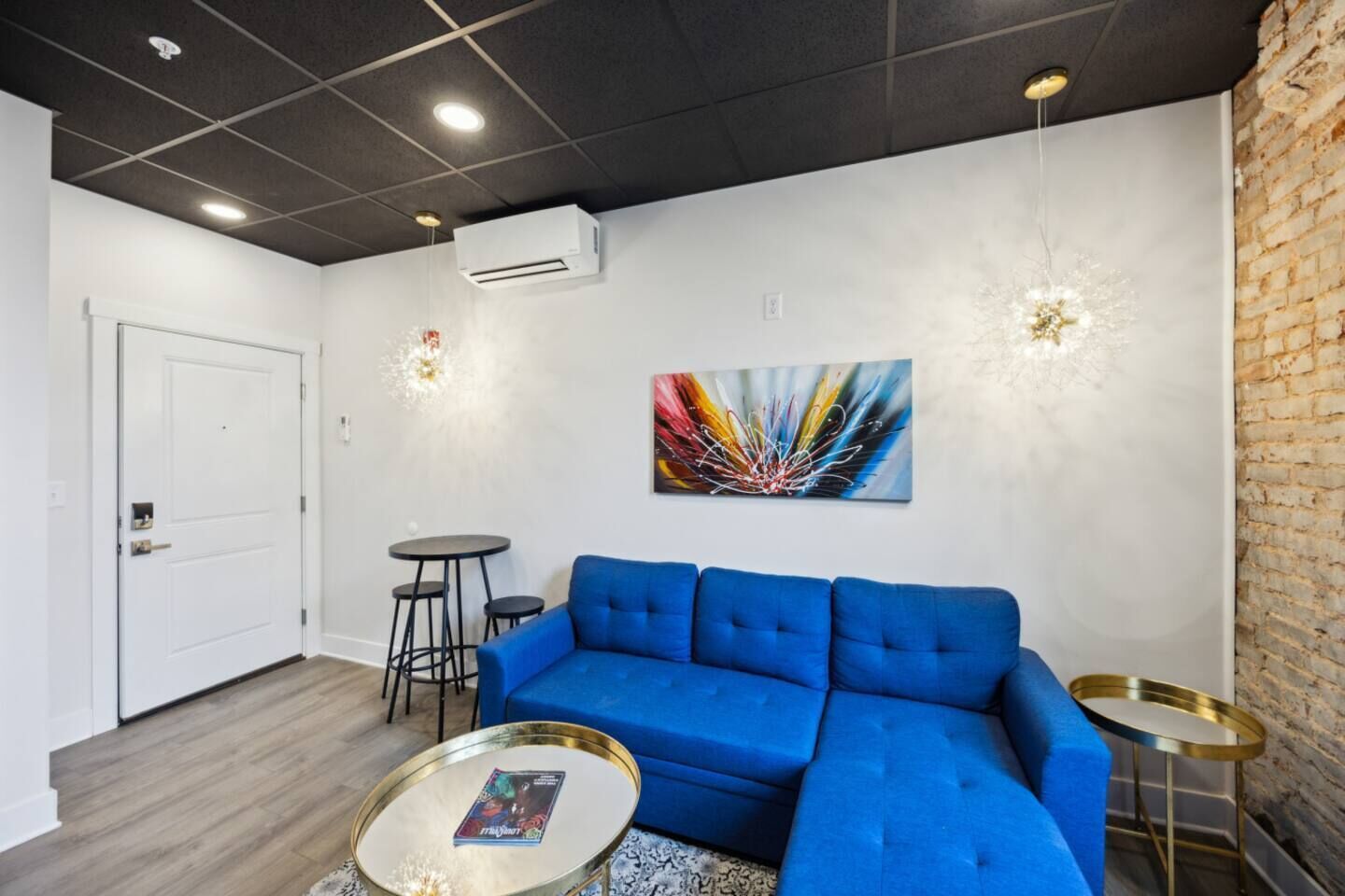 Un salon moderne avec un canapé bleu, une table basse et un tableau accroché au mur.
