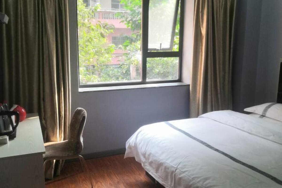 A hotel room with a bed, a desk, a chair, and a window with curtains.