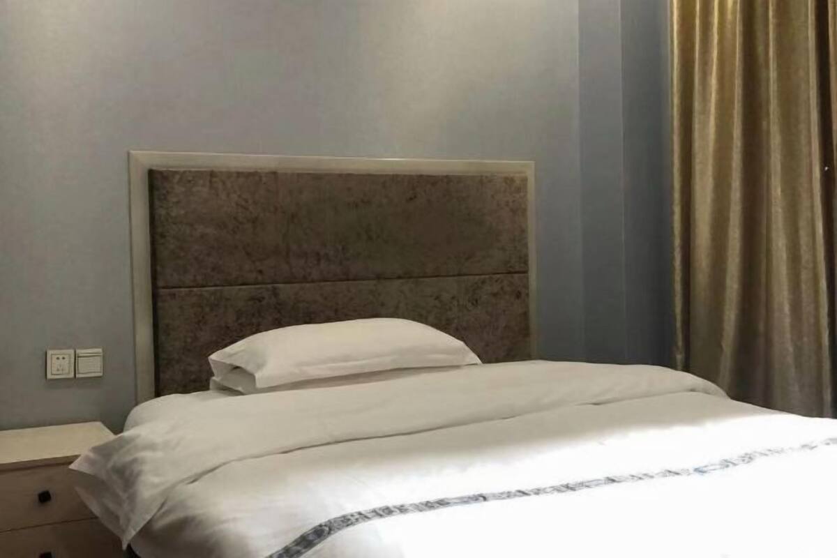 A hotel room with a bed, a nightstand, and a wall socket.