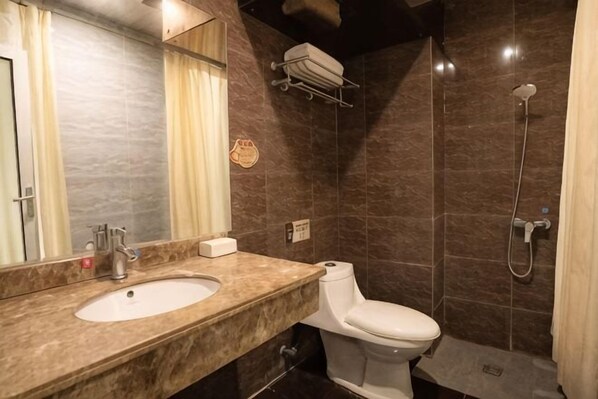 Une salle de bain avec un lavabo en marbre, des toilettes, une douche et un porte-serviettes.