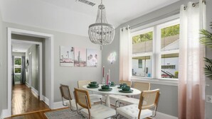 Un comedor con una mesa redonda, sillas blancas y una lámpara de araña.