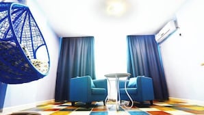 Una habitación con dos sofás azules, una silla colgante, una mesita pequeña y un suelo con baldosas de colores.