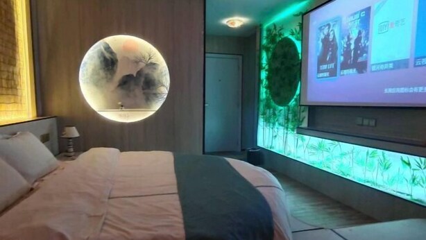 Un dormitorio con cama, un adorno redondo en la pared, una pantalla de proyección y un acuario instalado en la pared.
