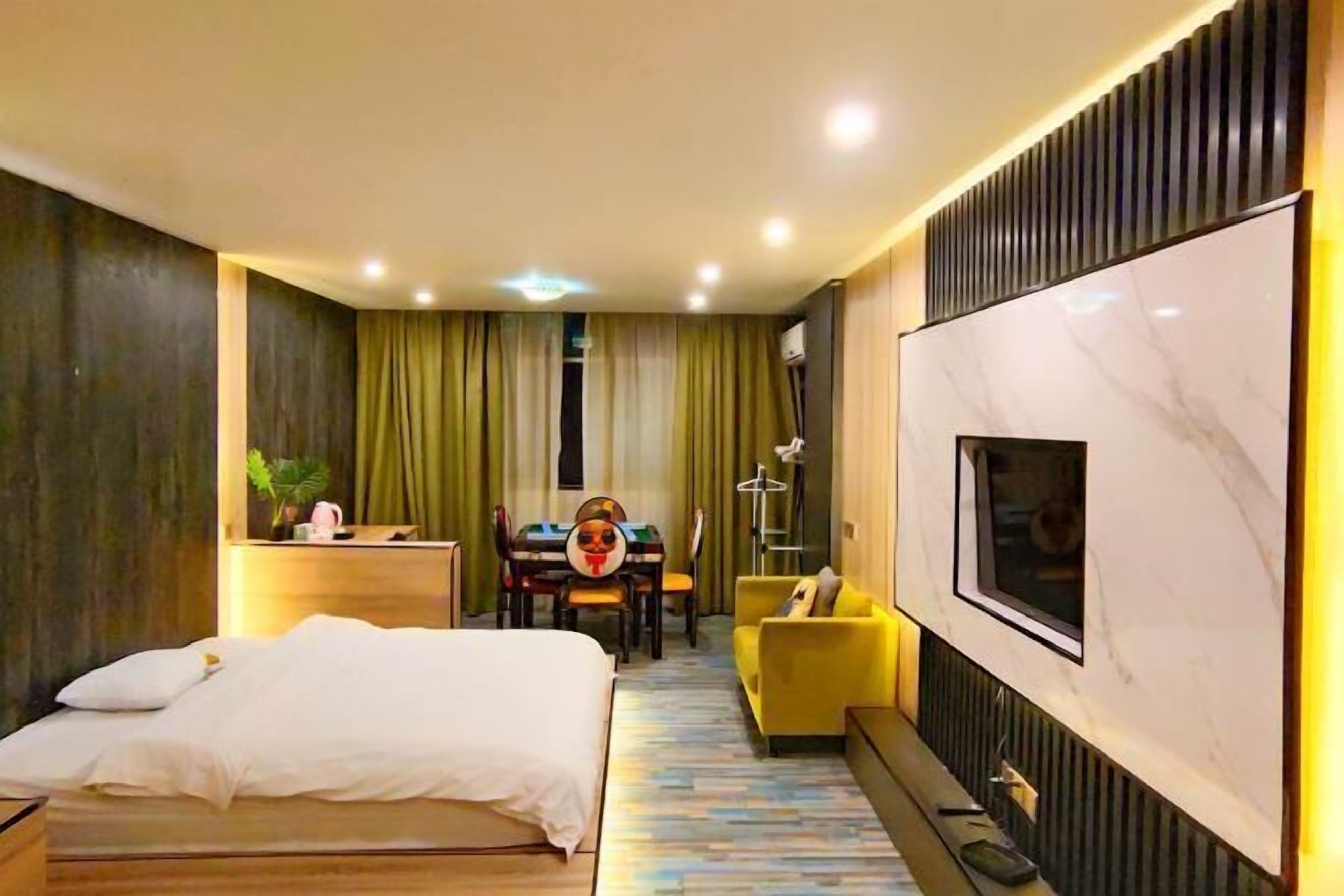 Una habitación de hotel moderna con una cama grande, un escritorio, un sillón amarillo y un televisor montado en la pared.