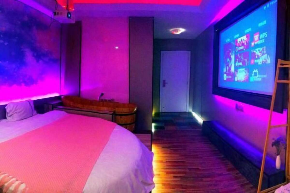 Habitació d'hotel amb un llit, una pantalla que mostra un menú i un terra de fusta.