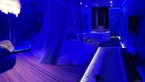 Una habitación con piso de madera, una bañera blanca y un ventanal grande.