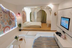 Una habitación de hotel moderna con cama, una mesita, televisión y un diseño de pared original.