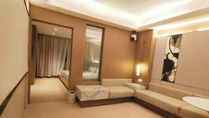 Una habitación de hotel moderna con un sofá, una mesita, un espejo y un cuadro en la pared.