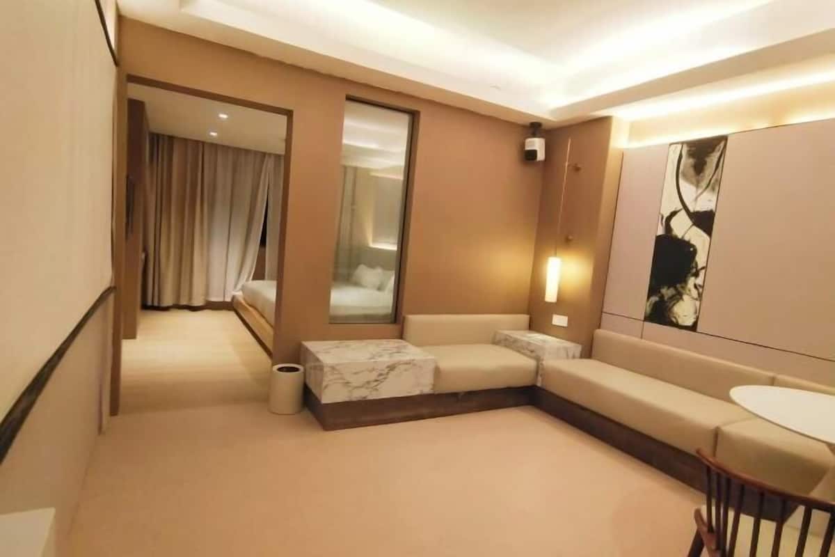 Una habitació d'hotel moderna amb un sofà, una taula petita, un mirall i un quadre a la paret.