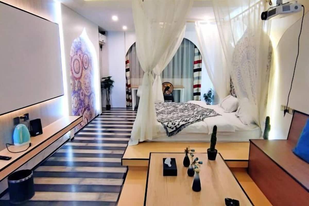 Habitació d'hotel moderna amb un llit, una taula de nit i una finestra gran amb cortines.