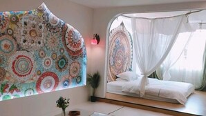 Un dormitorio con cama, mesita de noche, tapiz en la pared y dosel sobre la cama.
