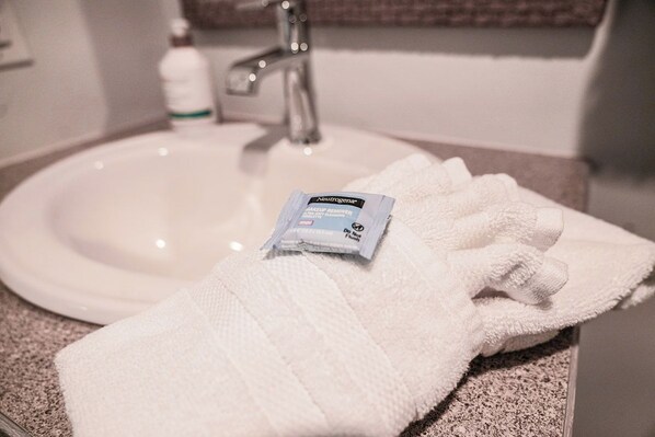 A white towel and a Neutrogena makeup remover packet on a bathroom counter.