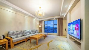 A hotel room with a sofa, a coffee table, a TV, and a large window with a view. - Dc cheng hotel (Beiliu)