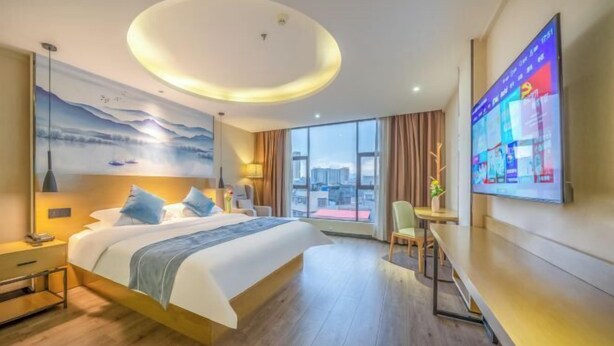 A modern hotel room with a large bed, a desk, and a TV on the wall. - Dc cheng hotel (Beiliu)