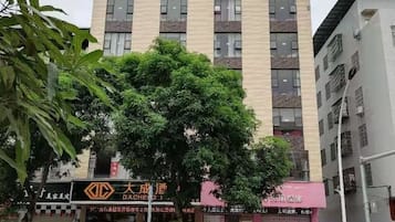 A multi-story building with a large tree in front.