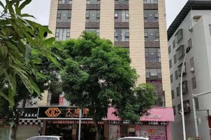 Un edificio de varios pisos con un gran árbol en primer plano.