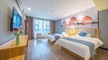 A hotel room with two beds, a desk, a chair, a TV, and a painting on the wall.