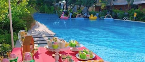 A poolside dining area with a table set for a meal, overlooking a swimming pool.